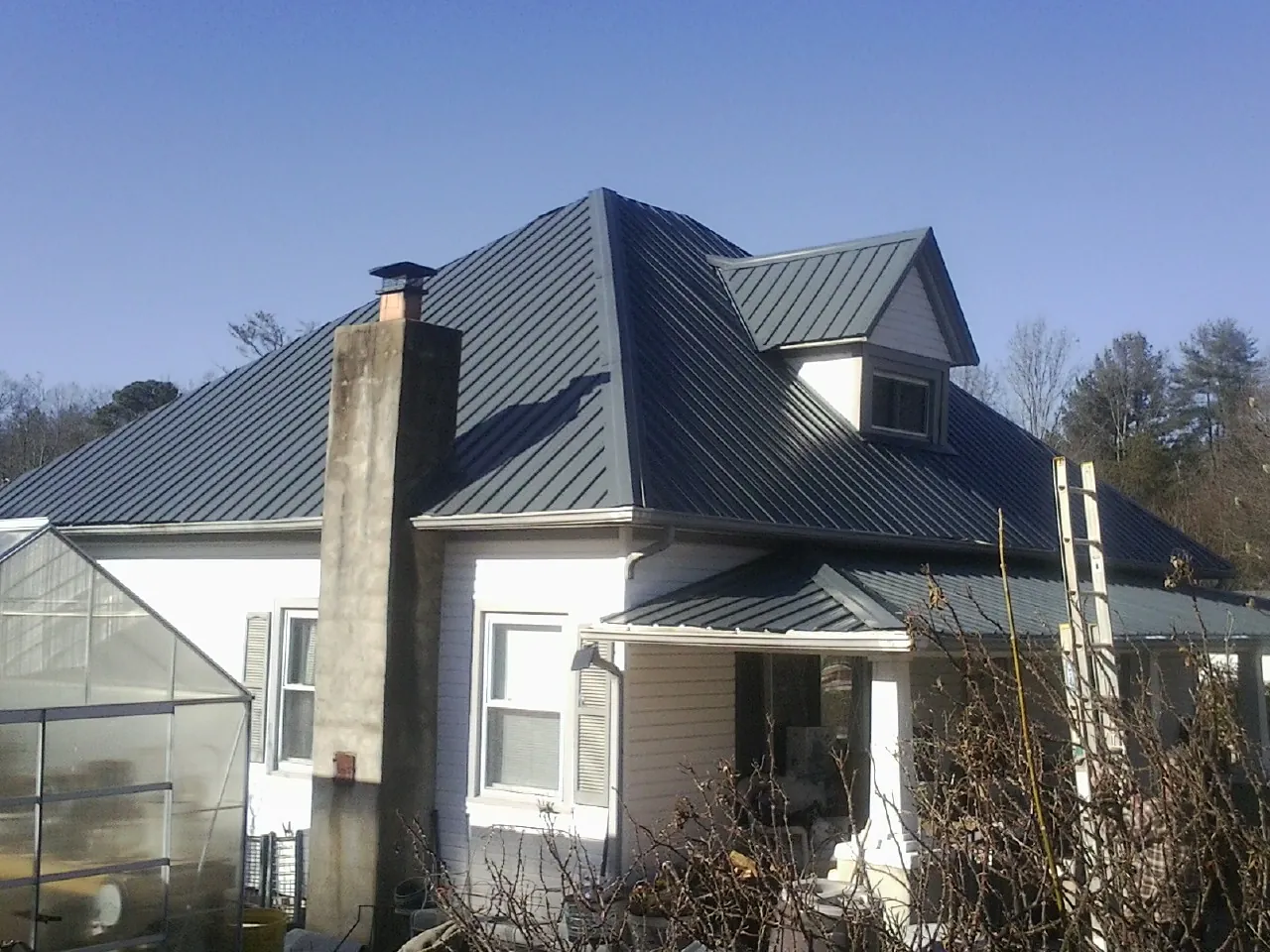 Dark blue standing seam metal roof on a white farmhouse with dormer — Slate & Tile Roof Repair by Roofing Brothers in Merrimac