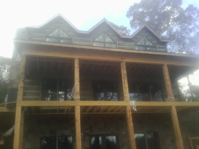 Dormers and porch framing on a large log home under construction — Roof Coating work by our crew in Merrimac