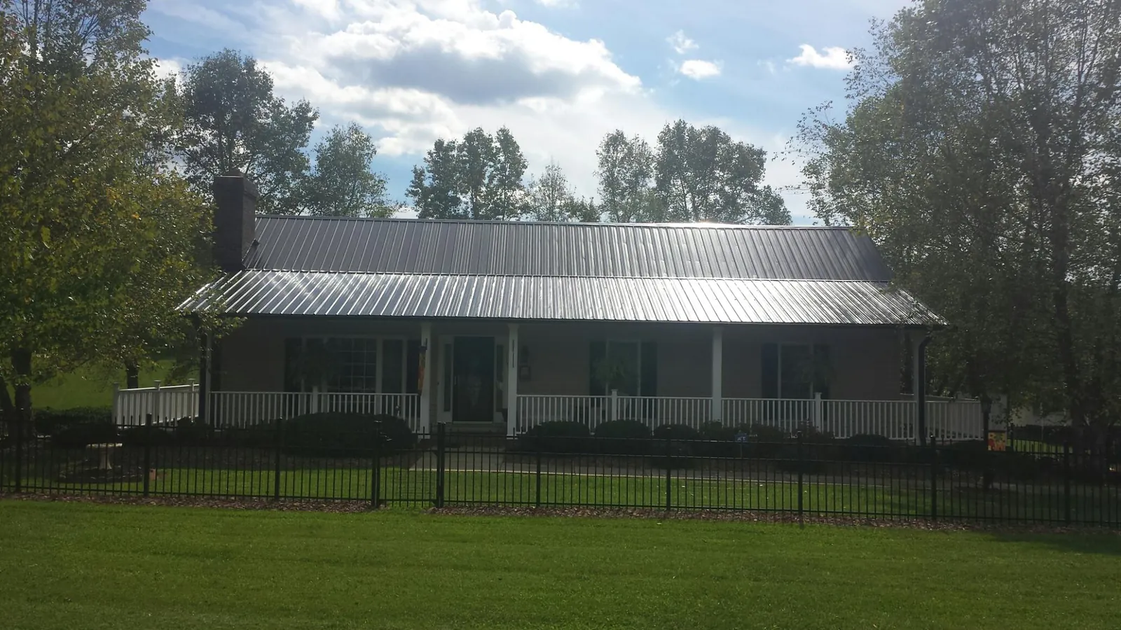Gray metal roof on a brick ranch with a full width front porch — Gutter Guard Installation work by our crew in Merrimac