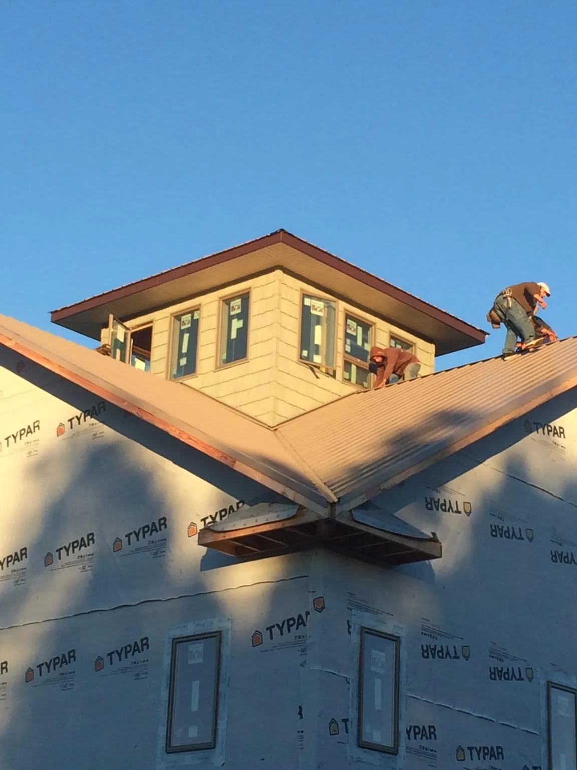 Roofers working around a rooftop cupola on a new metal roof at sunset — Roof Waterproofing in Merrimac by Roofing Brothers